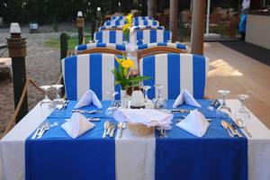 Fame Residence Lara & Spa Esstisch am Strand mit blau-weiß gestreiften Stühlen und Tischdecken.