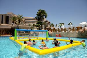 Gruppe von Erwachsenen spielt Volleyball im Pool des Fame Residence Lara & Spa Hotels.