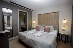 Schlafzimmer des Fame Residence Lara & Spa Hotels mit Bett, Spiegel und Nachttischen.