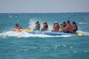 Gruppe von Leuten auf einem Boot im Meer, alle tragen orange Westen