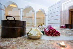 Saunaraum im Fame Residence Lara & Spa mit einer Schüssel Seife, einem Ölkrug und gestapelten Handtüchern.