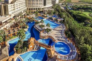 Luftaufnahme des Fame Residence Lara & Spa Hotels mit mehreren Swimmingpools und Sonnenliegen