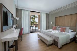Hotelzimmer im Fame Residence Lara & Spa mit Balkon, Bett, Schreibtisch und Fernseher.