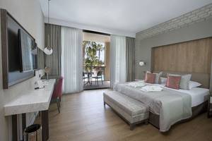Hotelzimmer im Fame Residence Lara & Spa mit Doppelbett, Balkon und Ausblick auf einen Swimmingpool.