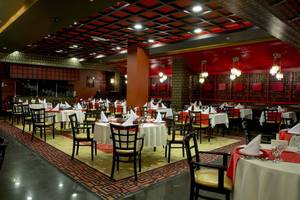 Innenansicht des Restaurants im Fame Residence Lara & Spa Hotel mit roten Wänden und Tischdecken.