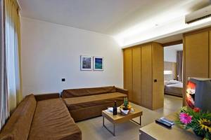 Loungebereich im Hotelzimmer mit zwei Sofas, einem Tisch, einem Fernseher und einem Bett im Hintergrund.