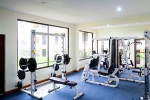 Fitnessraum im Occidental Papagayo Hotel mit verschiedenen Trainingsgeräten und großen Fenstern.