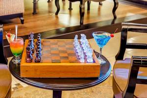 Ein holzner Tisch mit einem Schachbrett und zwei Cocktails auf dem Occidental Papagayo Hotel.