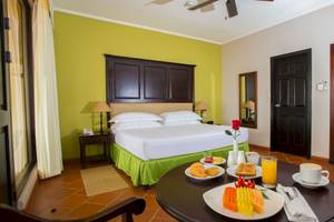 Hotelzimmer im Occidental Papagayo mit Frühstückstablett, Bett, Klimaanlage und Türen.