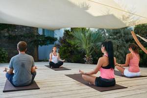 Vier Personen, die einen Yogakurs im Freien auf dem Island Hotel in Kreta absolvieren.