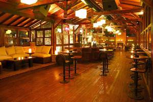Innenansicht der Bar im KoruMar Hotel De Luxe mit Holzboden, Sitzecken und einer Theke.