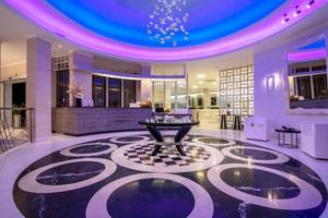 Empfangsbereich des La Mer Deluxe Hotel & Spa mit blauer und lila Beleuchtung und einem zentralen Tisch.