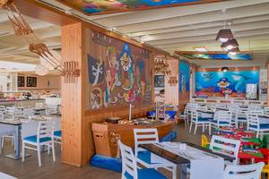 Innenansicht des Restaurants im H10 Suites Lanzarote Gardens Hotel mit bunten Wandmalereien und blauen Stühlen.