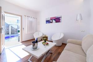 Wohnbereich des La Mer Deluxe Hotel & Spa mit Swimmingpool, weißer Einrichtung und Obstteller auf dem Tisch.