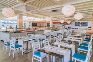 Restaurant-Innenbereich des H10 Suites Lanzarote Gardens mit blauen Stühlen und weißen Tischen.