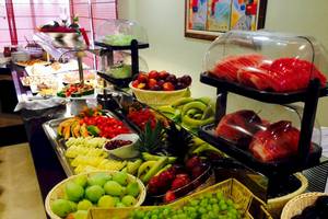 Buffet mit verschiedenen Früchten wie Äpfel, Bananen, Melonen und Trauben.