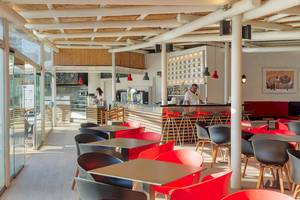 Innenansicht der Bar im H10 Suites Lanzarote Gardens mit roten Stühlen und Tischen.