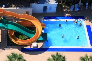 Foto des Schwimmbads im LABRANDA TMT Bodrum Hotel mit einer großen Wasserrutsche und mehreren Personen, die schwimmen.