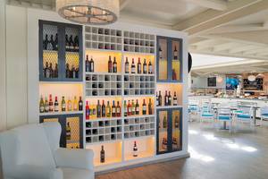Restaurant im H10 Suites Lanzarote Gardens mit Weinregal und Tischen.