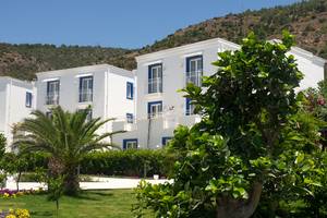 Außenansicht des Labranda TMT Bodrum Hotels mit weißen Gebäuden, blauen Fensterrahmen und umliegenden Pflanzen.