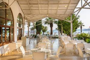 Terrasse im Freien des Labranda TMT Bodrum Hotels mit weißen Tischen und Stühlen.
