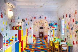 Ein buntes Kinderzimmer mit Puzzle-Fliesen auf dem Boden und bunten Handabdrücken an der Wand.