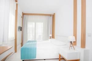 Schlafzimmer im LABRANDA TMT Bodrum Hotel mit weißem Bett, blauer Decke, zwei Lampen und weißem Nachttisch.