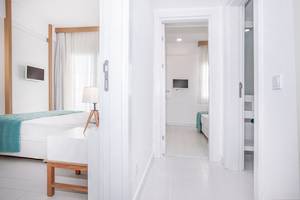 Innenansicht eines Zimmers im Labranda TMT Bodrum Hotel mit weißem Interieur, Bett, Tisch und Fernseher.