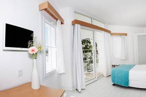 Innenansicht eines Zimmers im LABRANDA TMT Bodrum Hotel mit Bett, Fernseher und Balkonzugang