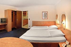 Hotelzimmer im Hamburg Mitte mit Schreibtisch, Fernseher, Betten und Stühlen.