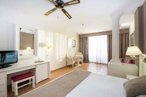Innenansicht eines Hotelzimmers im Bahia Principe Sunlight Costa Adeje, mit Bett, Schreibtisch, Fernseher und Möbeln.
