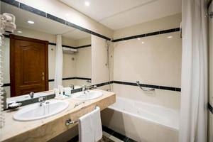 Ein Badezimmer im Bahia Principe Sunlight Costa Adeje mit einer Badewanne, zwei Waschbecken und einem großen Spiegel.