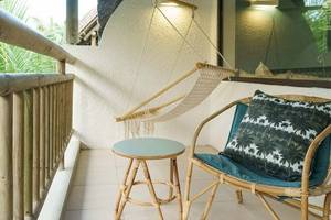 Balkon des Recif Attitude Hotels mit Korbstuhl, Kissen, kleinem Tisch und Seilschaukel.