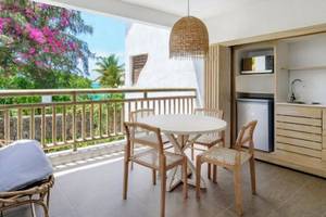 Balkon des Recif Attitude Hotels mit Tisch, Stühlen, Kissen und Küchenzeile.