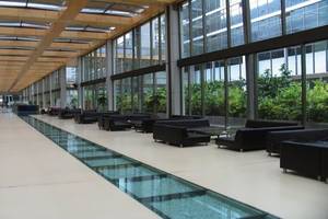 Lobby des Nirvana Cosmopolitan Hotels mit langen Glasflur und schwarzen Sofas.