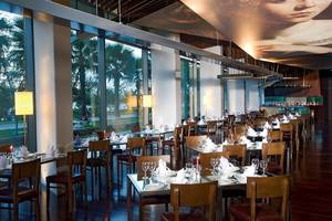 Innenansicht des Restaurants im Nirvana Cosmopolitan Hotel mit vollen Tischen und einer großen Wandmalerei.