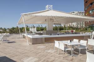 Foto der Terrasse des Nirvana Cosmopolitan Hotels mit einer großen weißen Überdachung und vielen weißen Tischen und Stühlen.
