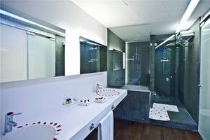 Badezimmer im Nirvana Cosmopolitan Hotel mit zwei Waschbecken, Dusche und Badewanne.