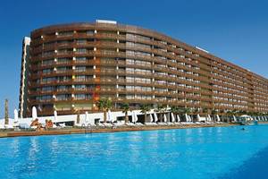 Außenansicht des Nirvana Cosmopolitan Hotels mit großem Swimmingpool und Sonnenliegen.