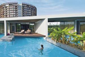 Schwimmbad und Loungebereich im Nirvana Cosmopolitan Hotel mit zwei Personen auf Liegen.