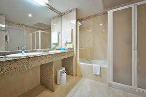 Badezimmer im MAC Puerto Marina Hotel mit zwei Waschbecken, Dusche und Badewanne.