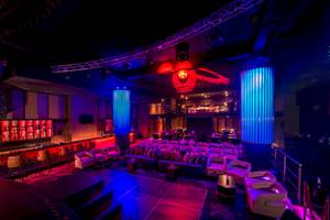 Lounge-Bereich im Hotel mit blauen und roten Lichtern, Sofas und einer Bar.