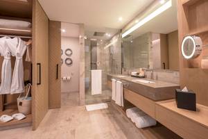 Ein modernes Badezimmer mit einer Glasdusche und einem Doppelwaschbecken, umgeben von Holzmöbeln und weißen Handtüchern.