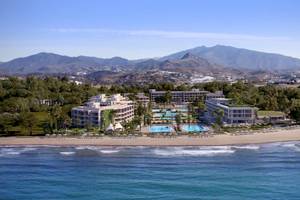 Luftaufnahme des Ikos Andalusia Hotels mit Swimmingpools und Bergen im Hintergrund.