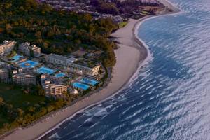 Luftaufnahme des Ikos Andalusia Hotels mit mehreren Swimmingpools und einer Küste.