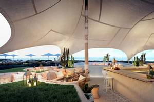 Außenloungebereich des Ikos Andalusia Hotels mit Blick auf das Meer und Kakteen.