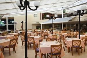 Innenansicht des Restaurants im SBH Royal Monica Hotel mit vollen Tischen und Stühlen.