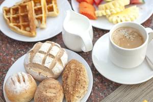 Frühstücksbuffet mit Kaffee, Obst, Waffeln, Brot und Säften auf einem Tisch im Hotel Beyond Resort Khao Lak.