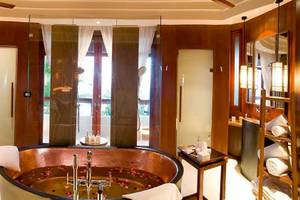 Badezimmer im Constance Halaveli Maldives mit großer Badewanne, Holzwänden und Glastür.