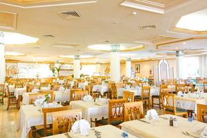 Innenansicht des Restaurants im El Mouradi Mahdia Hotel mit gedeckten Tischen und Stühlen.